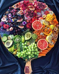 a large plate filled with lots of different types of fruits and vegetables on top of a blue cloth