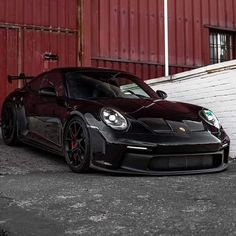 a black sports car parked in front of a red building