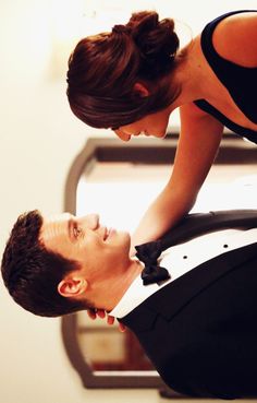 a man in a tuxedo is looking at his woman's face while they both look into each other's eyes