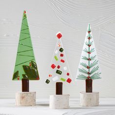 three small christmas trees sitting on top of each other in front of a white wall