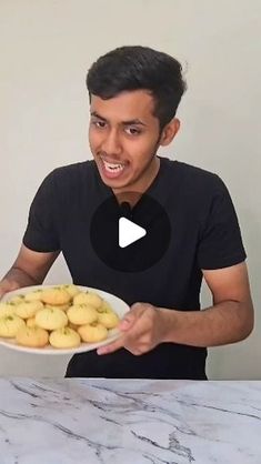 a young man holding a plate of cookies