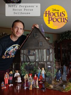 a man standing in front of a house with dolls on the table next to it