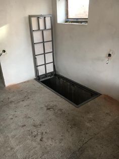 an empty room with a door and window in the corner, on concrete flooring