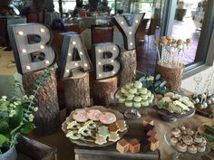 a baby shower is set up on a table with cookies and cupcakes in the shape of letters