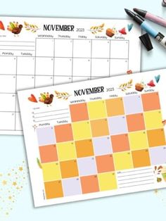 two calendars with autumn leaves on them next to markers and crayon pens