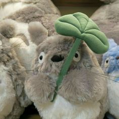 several stuffed animals are lined up in a row and one has a green leaf on it's head