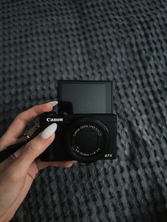 a person holding up a camera on top of a bed