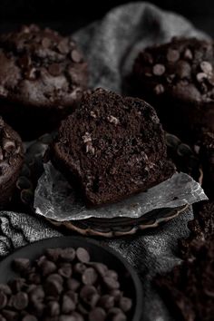 several chocolate muffins sitting on top of each other next to bowls of chocolate chips