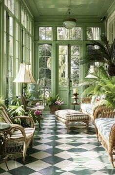 a room with green walls and lots of plants on the windowsills, two wicker couches in front of a checkered floor