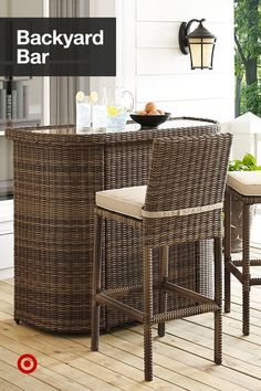 a wicker bar set with two stools on a deck next to a table and chairs