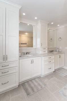 a large bathroom with white cabinets and marble counter tops, along with an area rug on the floor