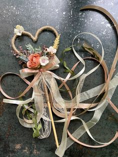 an arrangement of ribbons and flowers on a table with a heart shaped object in the middle