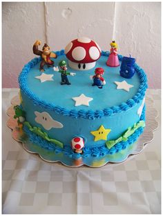 a blue cake with mario and friends on it sitting on a checkered tablecloth