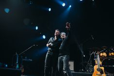 two men standing on stage with their arms in the air