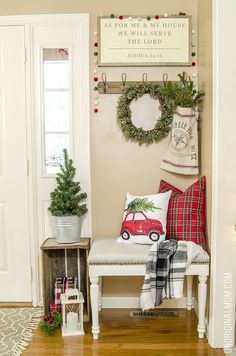 a white bench sitting in front of a christmas wreath on the wall next to a red car