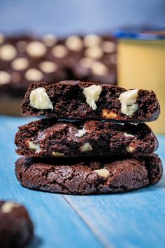 three chocolate cookies stacked on top of each other next to a glass of milk and some white chocolate chips