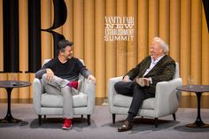 two men sitting in chairs talking to each other