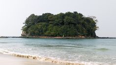 an island in the middle of the ocean with trees on it's top and water below