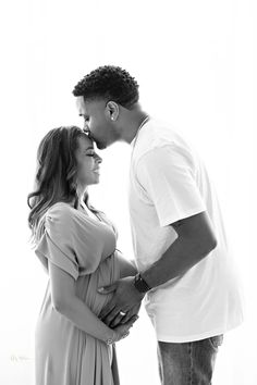 a man and woman standing next to each other in front of a white wall together