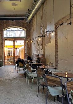 an empty restaurant with tables and chairs in front of a large open door that leads to the outside