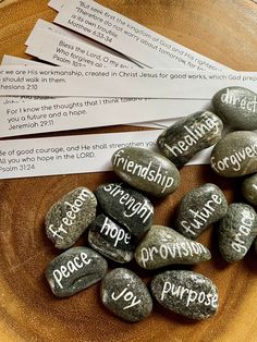 rocks with words written on them sitting on top of a wooden bowl filled with paper