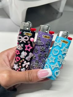 a person holding four lighters in their hand with bows and jewels on the covers