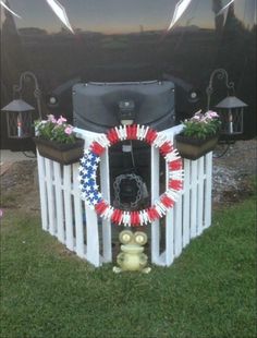 an american flag wreath on top of a white fence in front of a black car