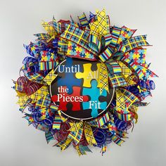 a multicolored puzzle piece wreath with the words until the pieces fit on it