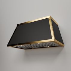 a black and gold square light fixture on a gray wall with dim lighting underneath it