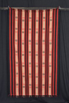 a red and black striped blanket hanging on a wall