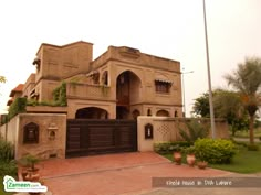 a large house that is in the middle of some bushes and trees with potted plants on it