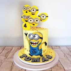 a three tiered cake with yellow frosting and minion decorations on it's top