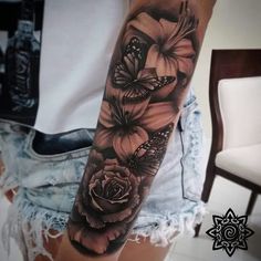 a woman's arm with black and white tattoos on it, flowers and butterflies