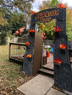 the entrance to an amusement park with fake flowers on it's sides and trees in the background