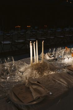 the table is set with wine glasses, candles and napkins for an elegant dinner