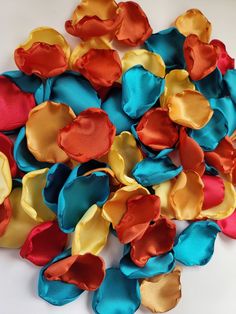 several different colors of satin flowers on a white surface