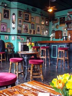 the inside of a restaurant with tables and chairs, pictures on the wall and flowers in vases