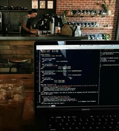 a laptop computer sitting on top of a wooden table next to a cup of coffee