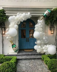 a blue front door with white balloons on it and a champagne bottle in the doorway