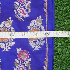 a measuring tape is in front of a blue cloth with flowers and leaves on it