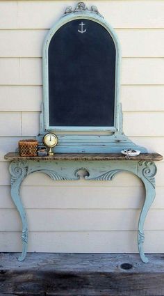 an old blue vanity with a chalkboard on the top and mirror above it in front of a white house