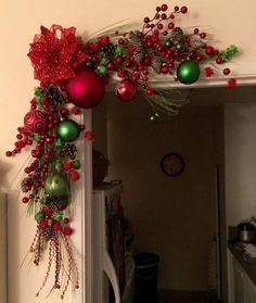 a door decorated with red and green christmas balls, ornaments and greenery hanging from it's side