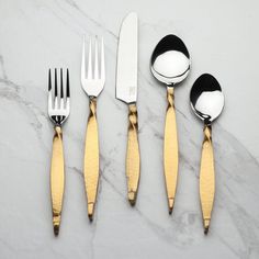 four forks, two spoons and one knife on a marble counter top with gold accents