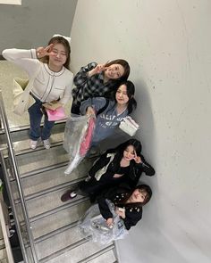 four girls are standing on an escalator and one girl is holding a plastic bag