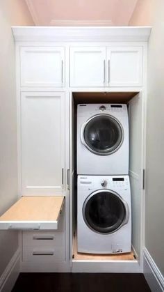 a white washer and dryer in a small room with built - in cabinets