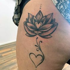 a woman's thigh with a lotus flower and heart tattoo on the side of her leg