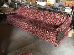 a red and black couch sitting in a garage next to a table with tools on it