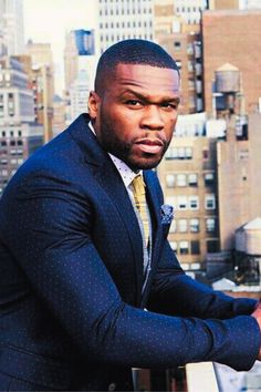 a man in a suit and tie standing on top of a building looking at the camera