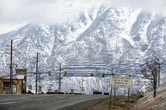 the mountains are covered in snow as cars drive down the road