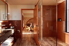 a bathroom with wooden floors and tile walls, along with a walk - in shower